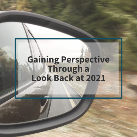 Picture of a rearview mirror with the words "Gaining Perspective Through a Look Back at 2021" written above it